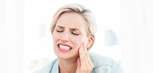 Woman holding cheek painfully