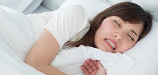 Woman grinding teeth during sleep