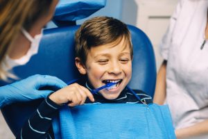 little boy brushing teeth at dentist